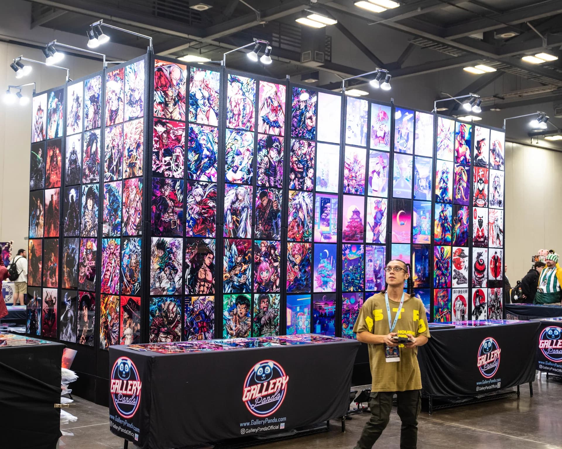 A Matsuricon vendor booth displays a wall of brightly lit anime and pop-culture prints.