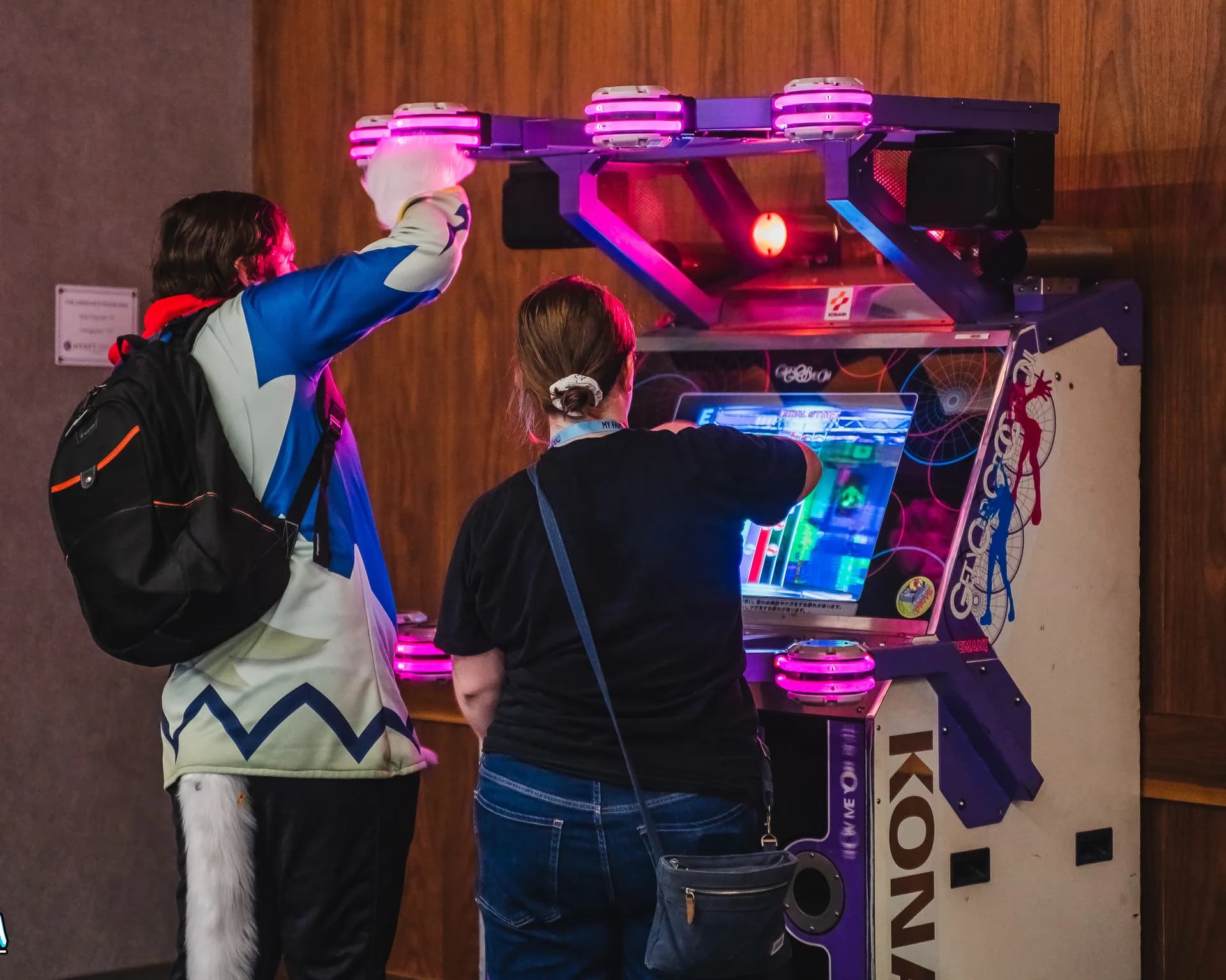Two Matsuricon attendees play a colorful touch-screen rhythm arcade cabinet together.