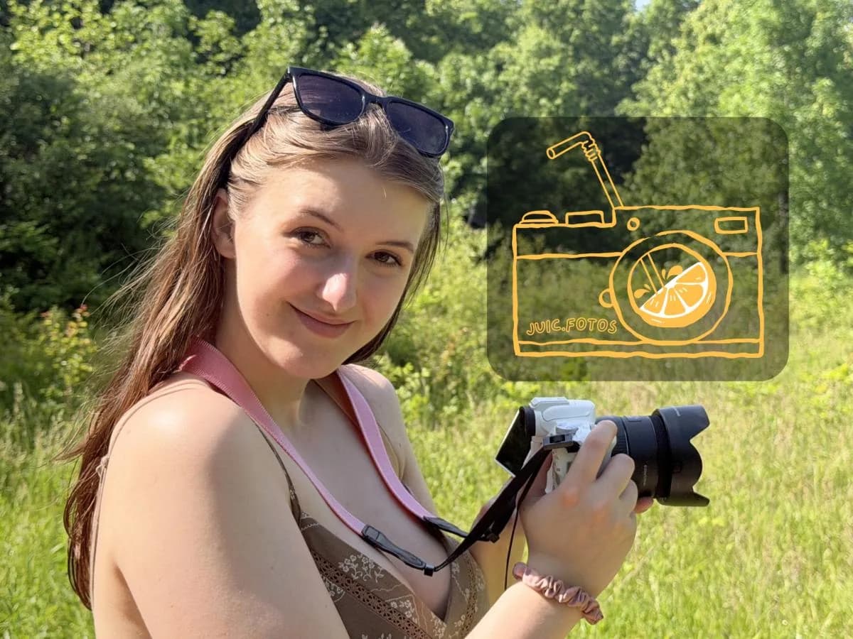 Portrait of Lora Hackworth holding a camera outdoors.